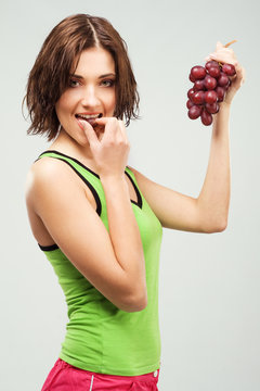 Beautiful sporty woman eating grapes