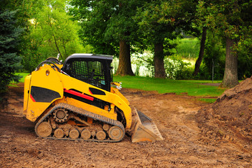 yellow bulldozer, tractor fitted with a dozer blade, on soil land in green farm