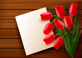 Red tulips and blank card  on old wooden board.
