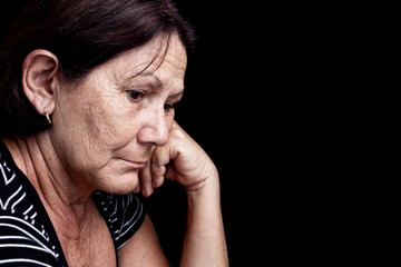 Sad and worried old woman isolated on black