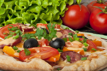 Closeup of pizza with tomatoes, cheese, black olives and peppers