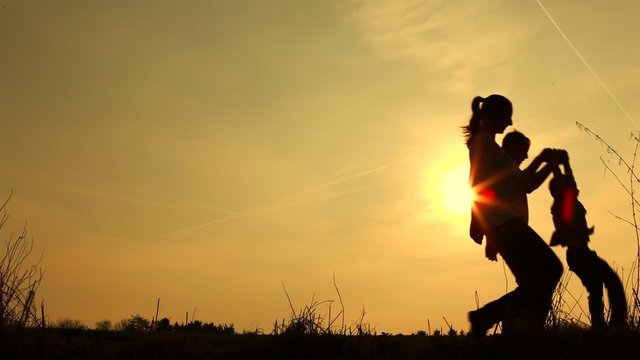 Silhouetted happy family playing walking swinging game with their son 