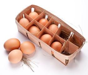 Eggs with a straw in a wooden basket on a white background.