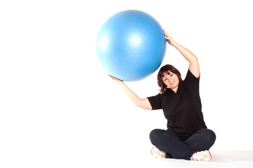 Shot of a overweight young woman exercise on fitness ball agains