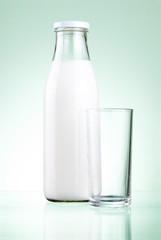 Bottle of fresh milk and blank glass on a green background