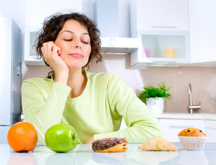 Diet. Beautiful Young Woman choosing between Fruits and Sweets