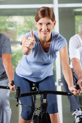 Frau im Fitnesscenter hält Daumen hoch