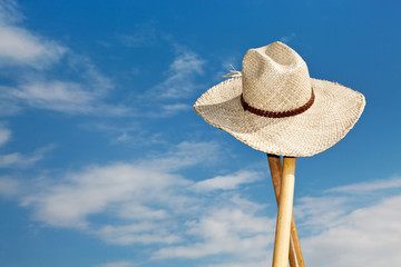 Straw hat hangs on the stalk