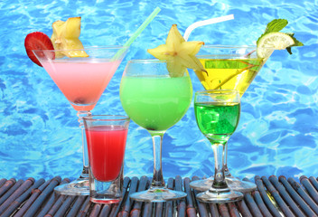 Glasses of cocktails on table on blue sea background