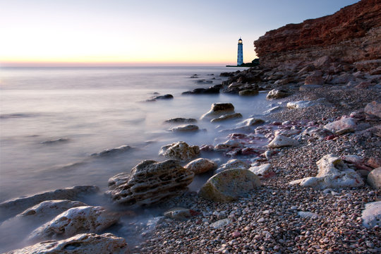 Beautiful sea beach with lighthouse and clear sky at the sunset