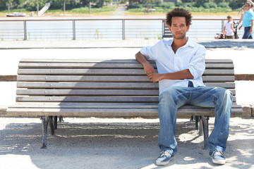 Obraz premium Young man sitting on a public bench