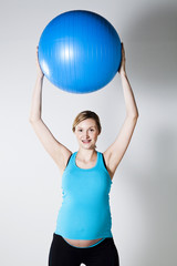 Fototapeta premium Pregnant woman stretching with fitness ball
