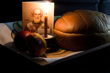 Easter eggs, a burning candle on a black background