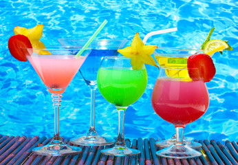 Glasses of cocktails on table on blue sea background