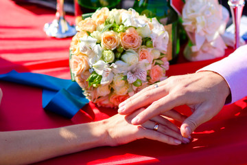 hands of bride and groom newlyweds on red wedding table is brida
