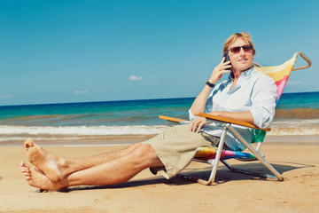 Business man calling by cell phone on the beach in Hawaii