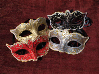 Four misked colour masquerade masks on red