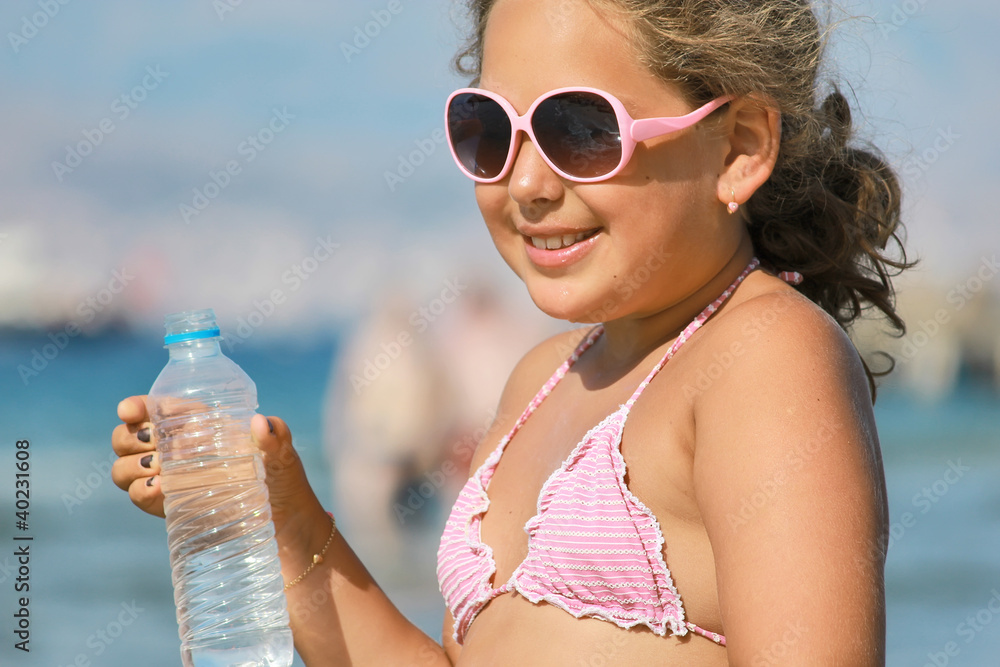 Wall mural girl drinking water from the bottle on the beach