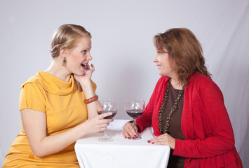 Mother and grown daughter  with glasses of wine