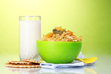 tasty cornflakes in green bowl and glass of milk