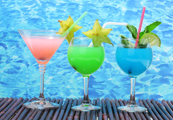 Glasses of cocktails on table on blue sea background