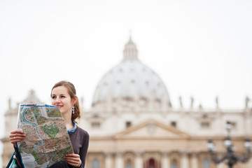 Pretty young female tourist studying a map at St. Peter's square