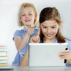Two cute girlfriends learning with books and touchpad