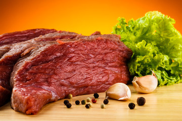 Raw beef on cutting board and vegetables