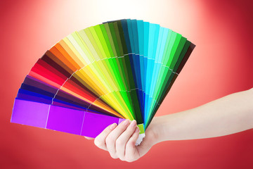 hand holding bright palette of colors on red background