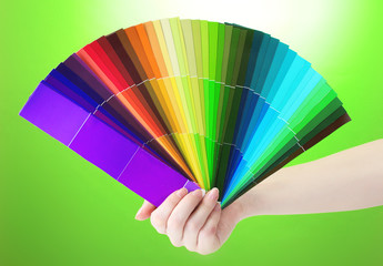 hand holding bright palette of colors on green background
