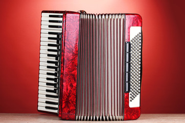 Retro accordion on wooden table on red background