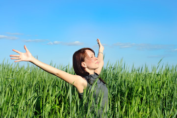 Naklejka na ściany i meble woman with hands raised up in the wheat field