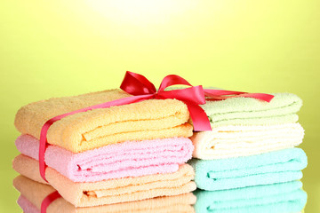 Obraz na płótnie Canvas Colorful towels with ribbon on green background