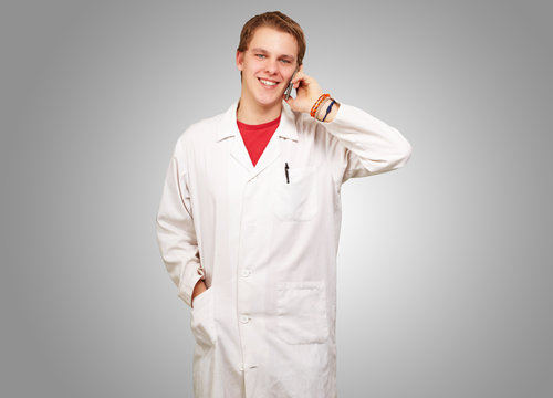 portrait of young academic talking on mobile over grey backgroun