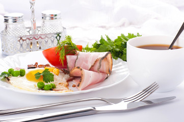 Bacon with fried eggs and tomatoes, a peas and corn