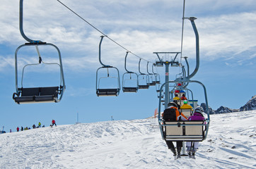 Sessellift in Skigebiet mit Skifahrern über Piste