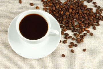 Cup of coffee with beans on natural cloth