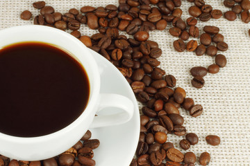 Cup of coffee with beans on natural cloth
