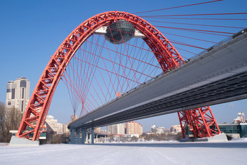 View of red arc bridge on frozen Moskva-river and many buildings
