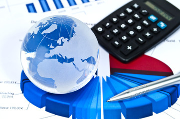 Glasglobus mit Statistiken, Kugelschreiber und Taschenrechner