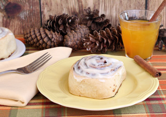 Delicious Cinnamon Bun with a glass of apple cider.