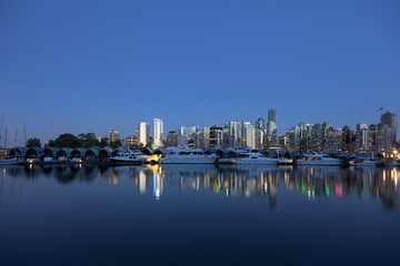 Fototapeta na wymiar Jachty i budynki odzwierciedlają na nabrzeżu Vancouvers