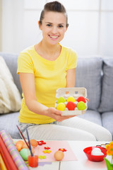 Obraz na płótnie Canvas Smiling woman showing tray with colorful Easter eggs