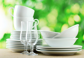 Clean dishes on wooden table on green background