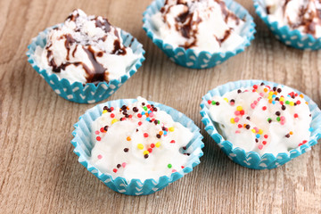 Creamy cupcakes on wooden background close-up