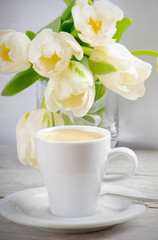 Obraz na płótnie Canvas Coffee cup and white tulips