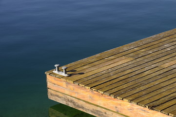 Wooden pontoon  and bollards on blue emerald water