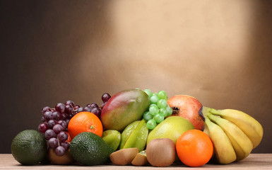 Assortment of exotic fruits on wooden table on brown background