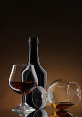 Glasses of brandy and bottle on brown background
