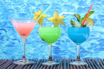 Glasses of cocktails on table on blue sea background